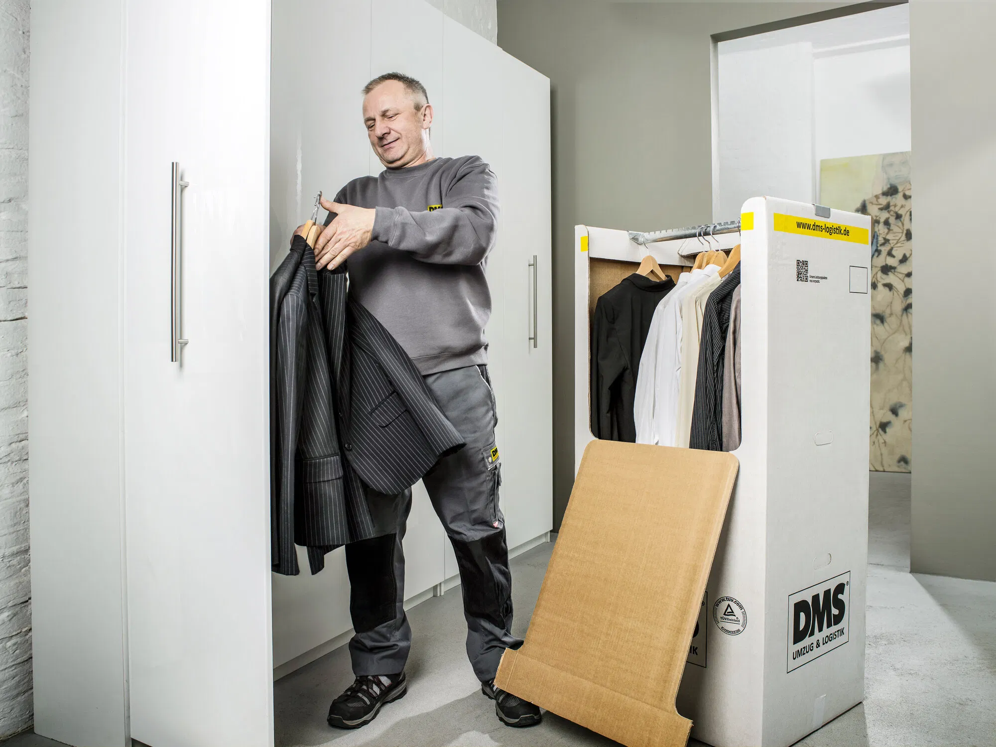 Mitarbeiter mit einem Anzug neben einem Kleiderkarton.
