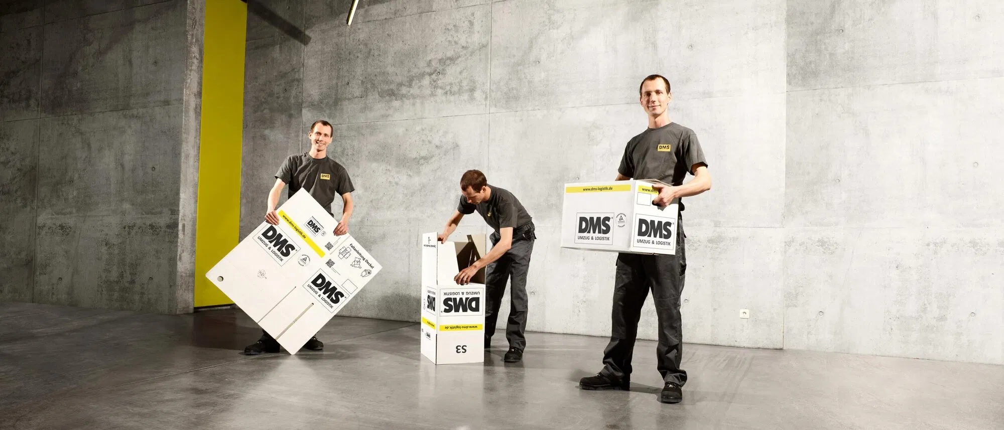 Drei Mitarbeiter beim Aufbauen von Umzugskartons.